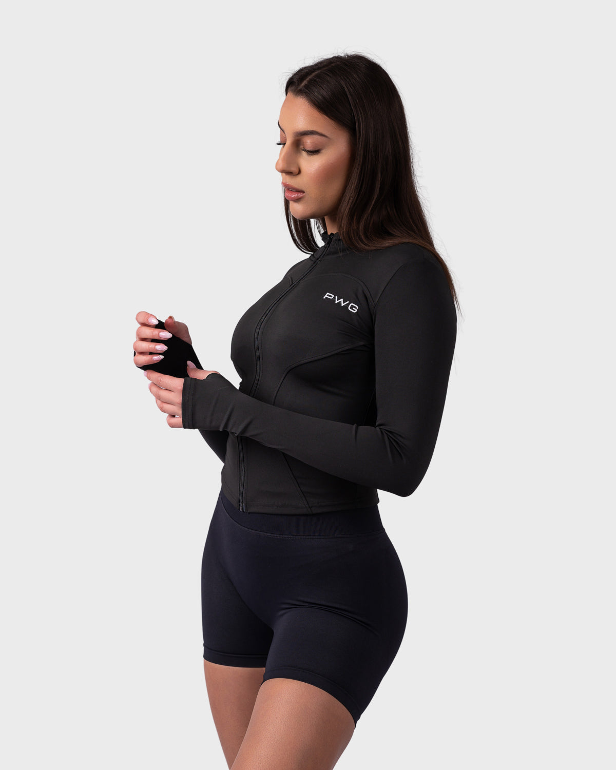Model wearing black sculpt fit jacket, side angle with thumbhole sleeves.