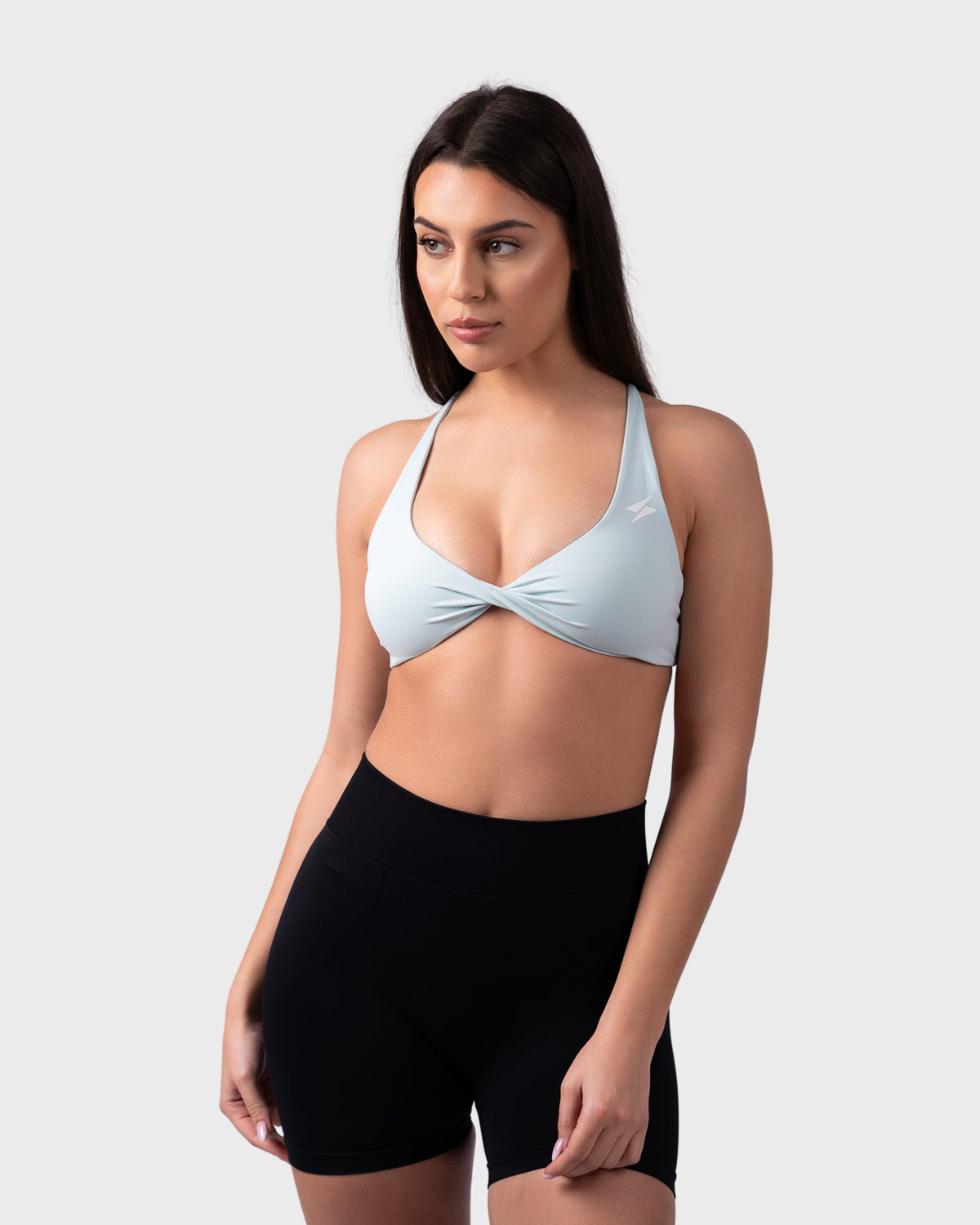 Full-body pose in celeste bra paired with black Form shorts, scoop neckline visible.