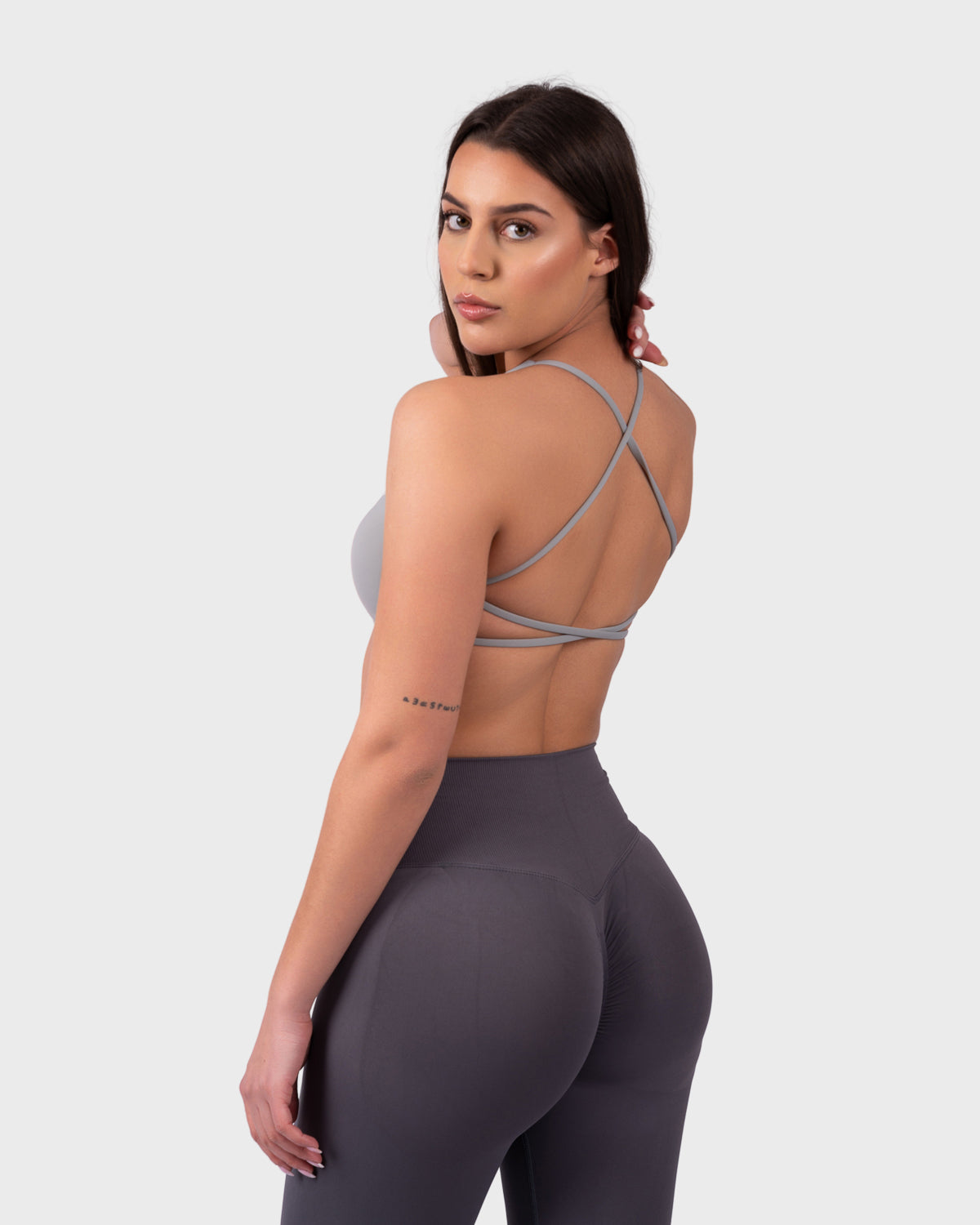 Back view of grey sports bra, cross-back straps and open-back design.
