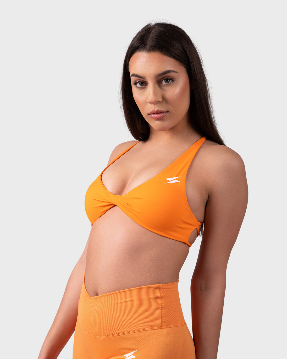 Angled view showing fit, scoop neck, and secure underband in neon orange.