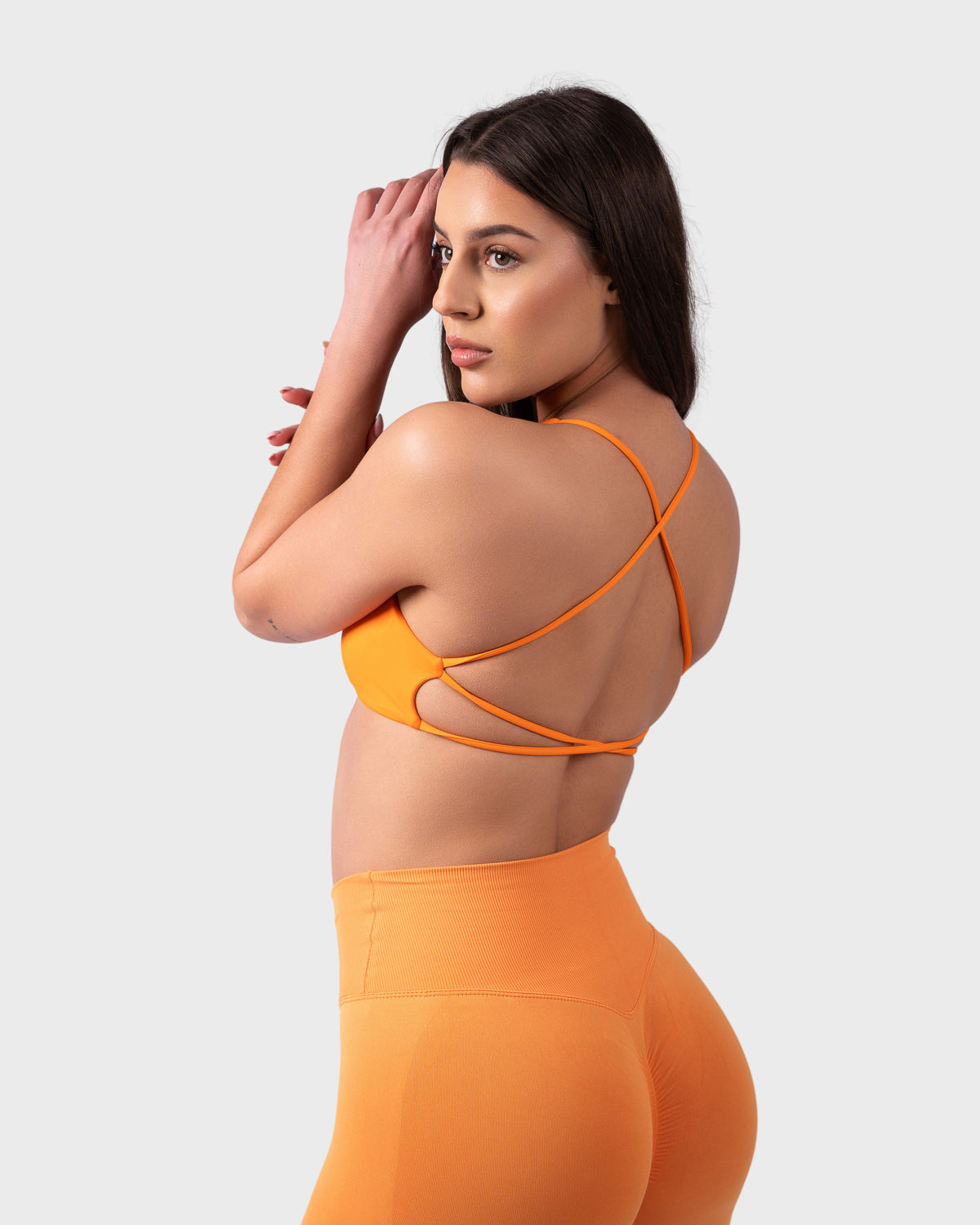Model adjusting strap in Evolve Backless Sports Bra, side-back profile.