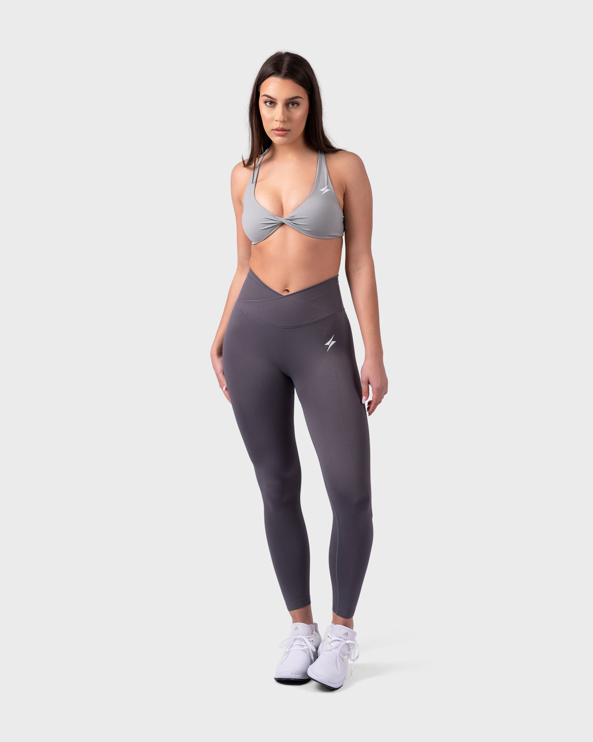 Model wearing Evolve V-Sculpt Leggings in onyx with grey backless bra, front stance.