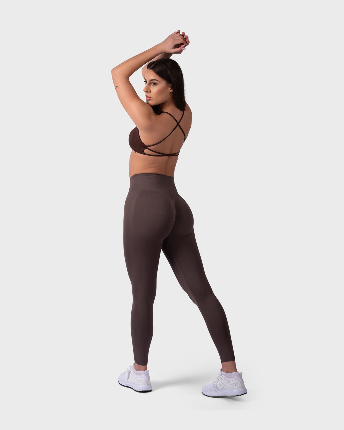 Full-body view of Evolve V-Sculpt Leggings in mocha with brown backless bra, arm raised.