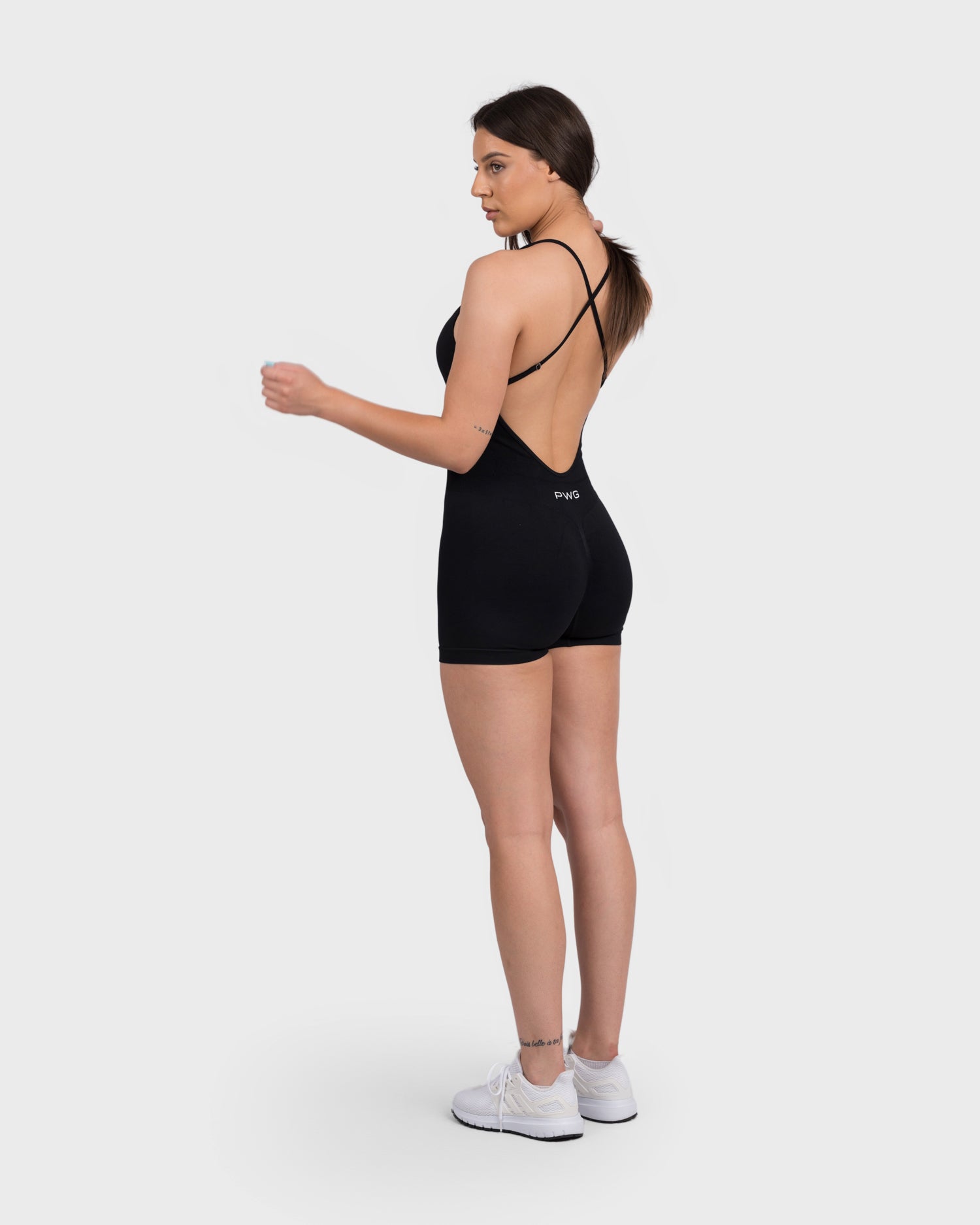 FlexActive Jumpsuit from PWG Active in black, model posing with arm slightly raised.