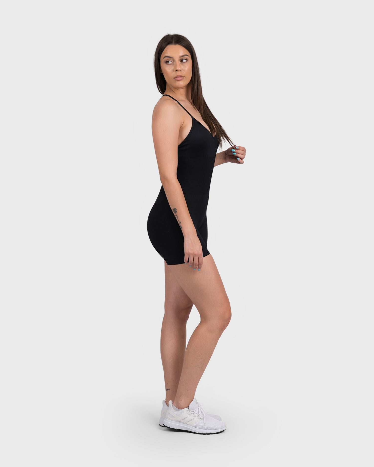 Angled pose in FlexActive black jumpsuit, highlighting waistline and leg fit.