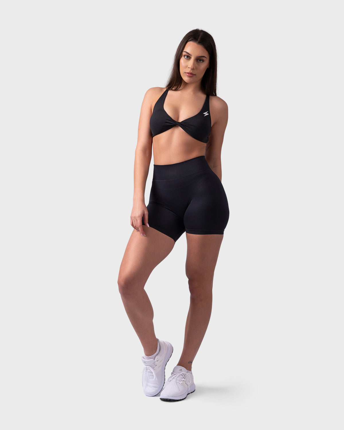 Model wearing black Evolve Backless Bra and Form Sculpting shorts, front-facing pose with hand on hip.