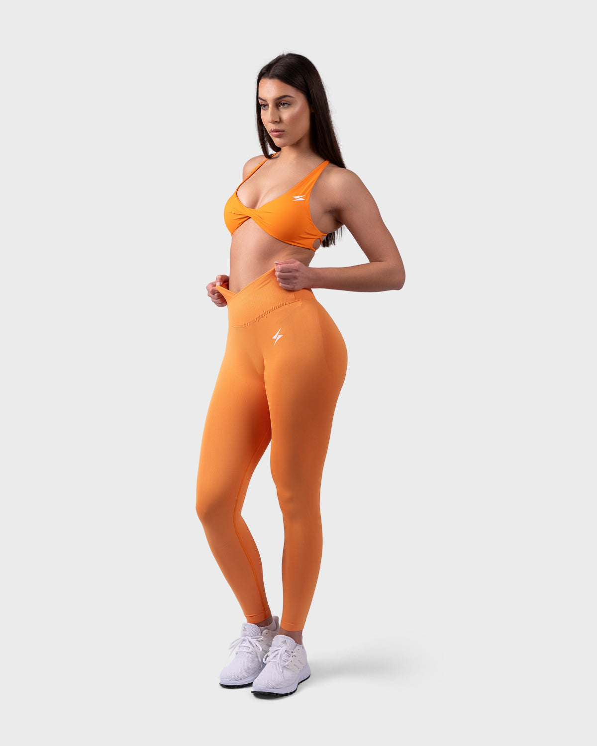 Full-body outfit featuring Evolve V-Sculpt Leggings in bright orange, paired with matching top.
