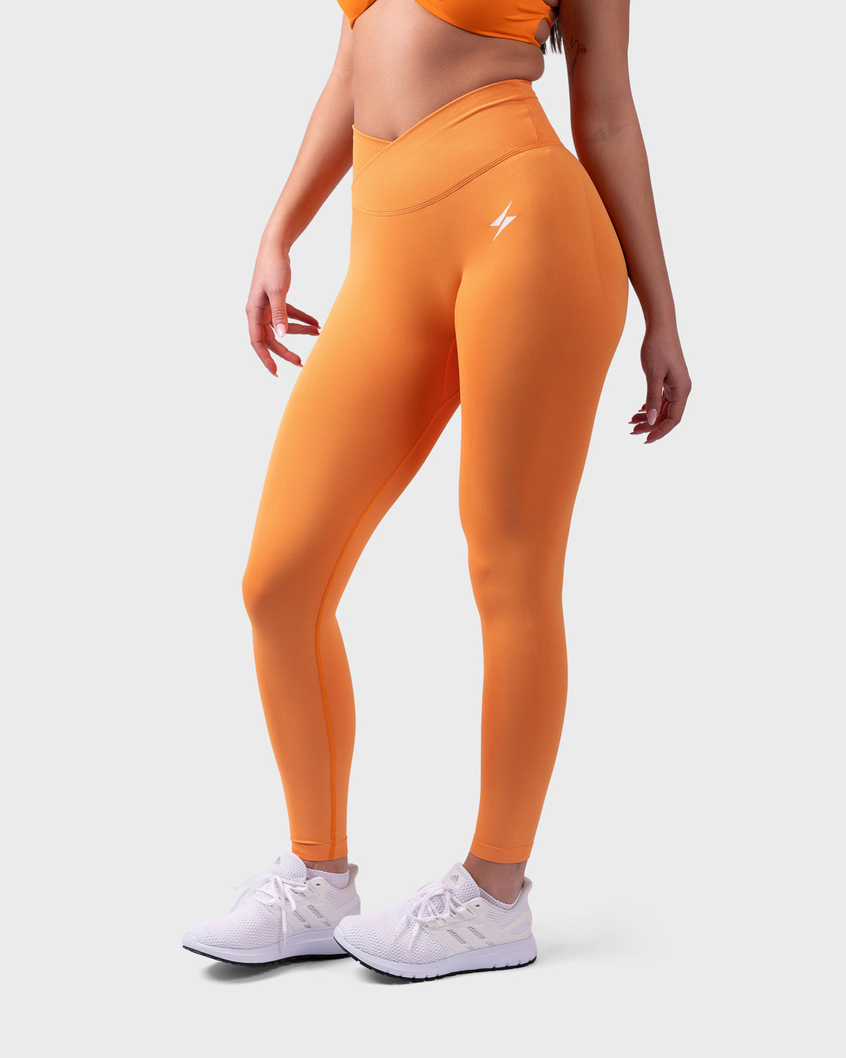Side pose in bright orange Evolve V-Sculpt Leggings, flattering waistband and stretch fabric.