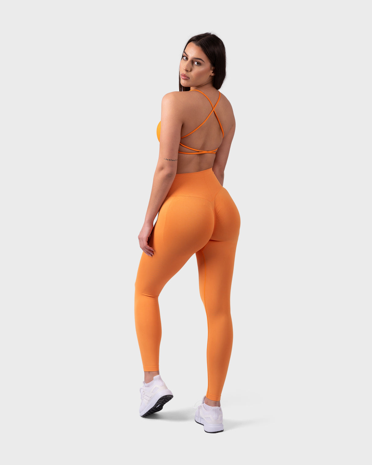 Back angle of Evolve Leggings in bright orange, showcasing glute-contour and sleek finish.