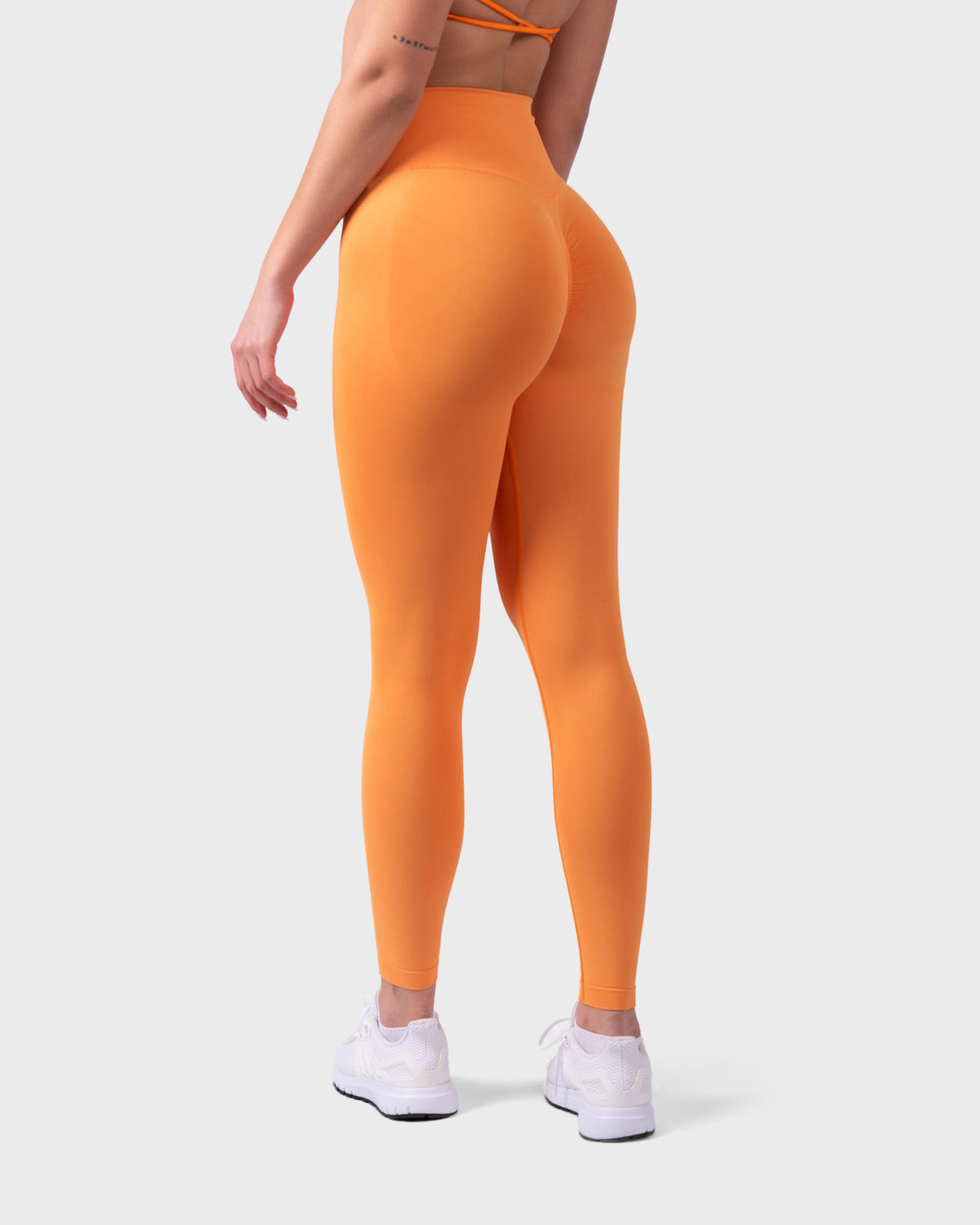 Rear view of bright orange Evolve Leggings, high-rise sculpting fit with full-length legs.