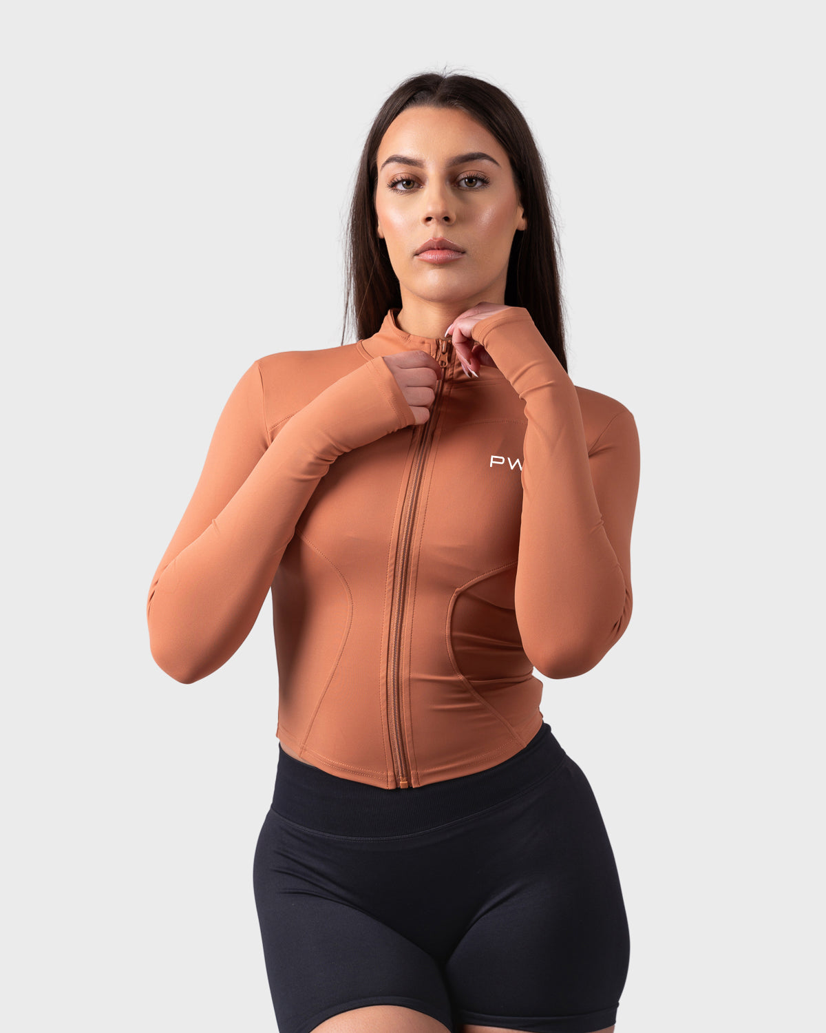 Model zipping up caramel toffee jacket, showcasing sculpted fit and snug collar.