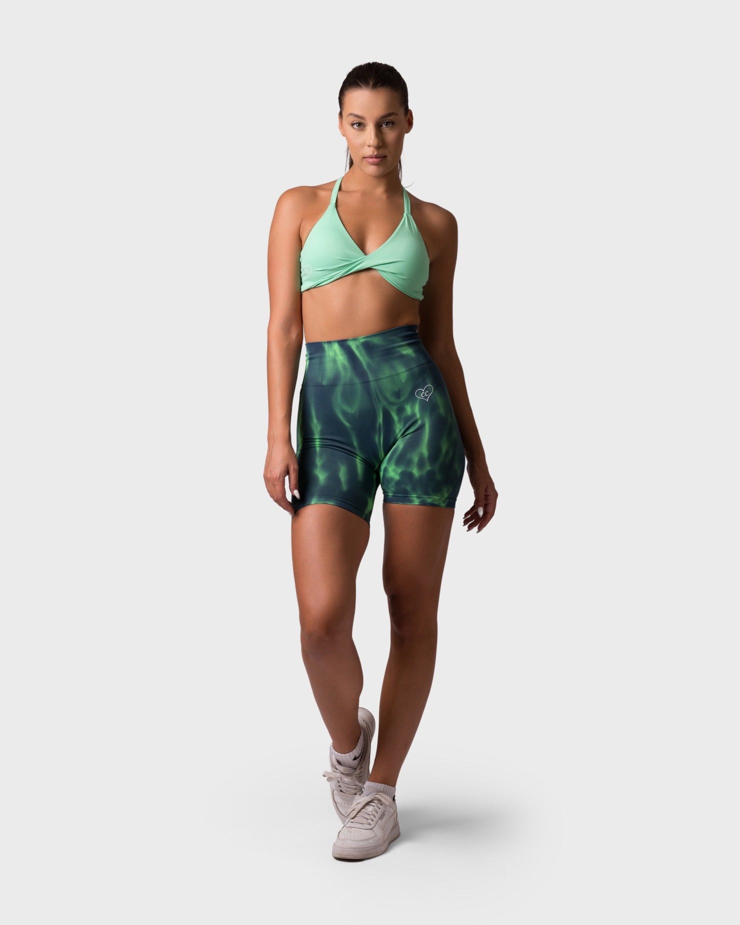 Full-body front view showing lime sports bra and green shorts, standing pose.