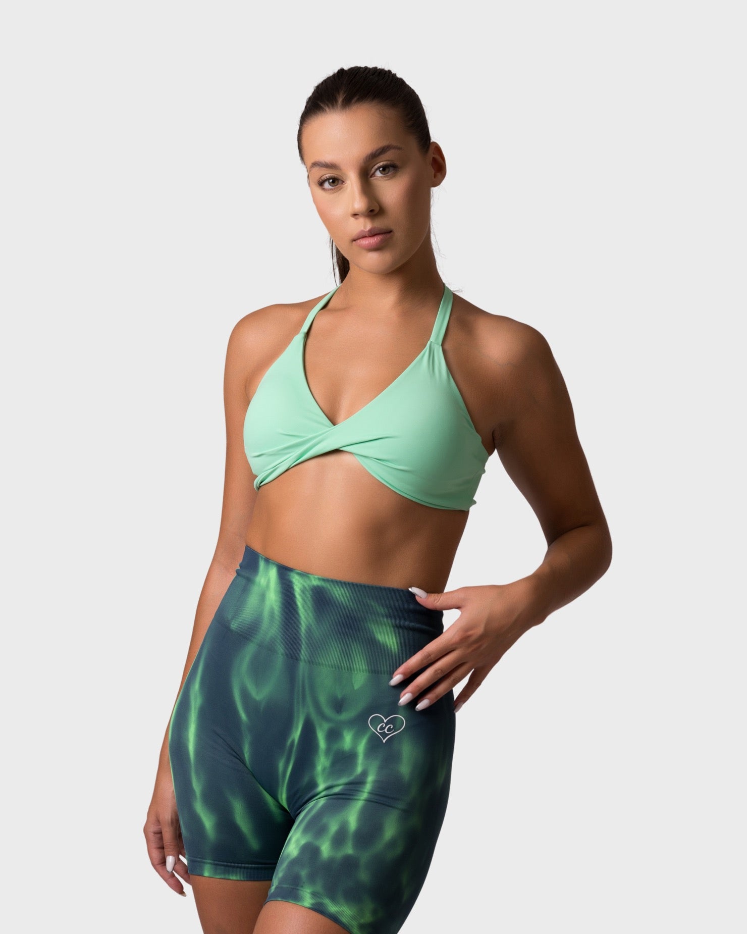 PWG x CC lime green knitted sports bra with twist-front, paired with green patterned shorts.