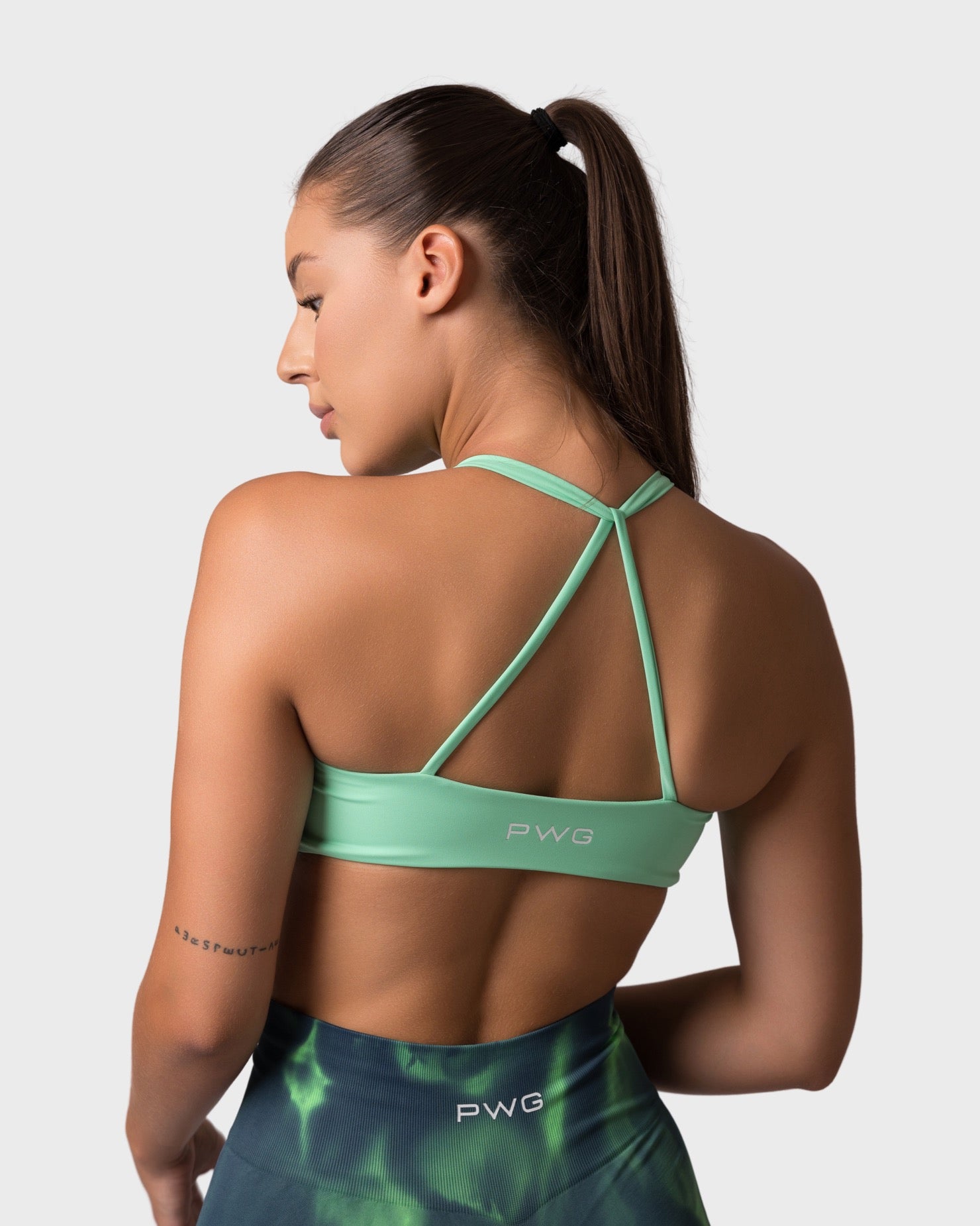 Back view of lime green sports bra with thin crisscross straps.