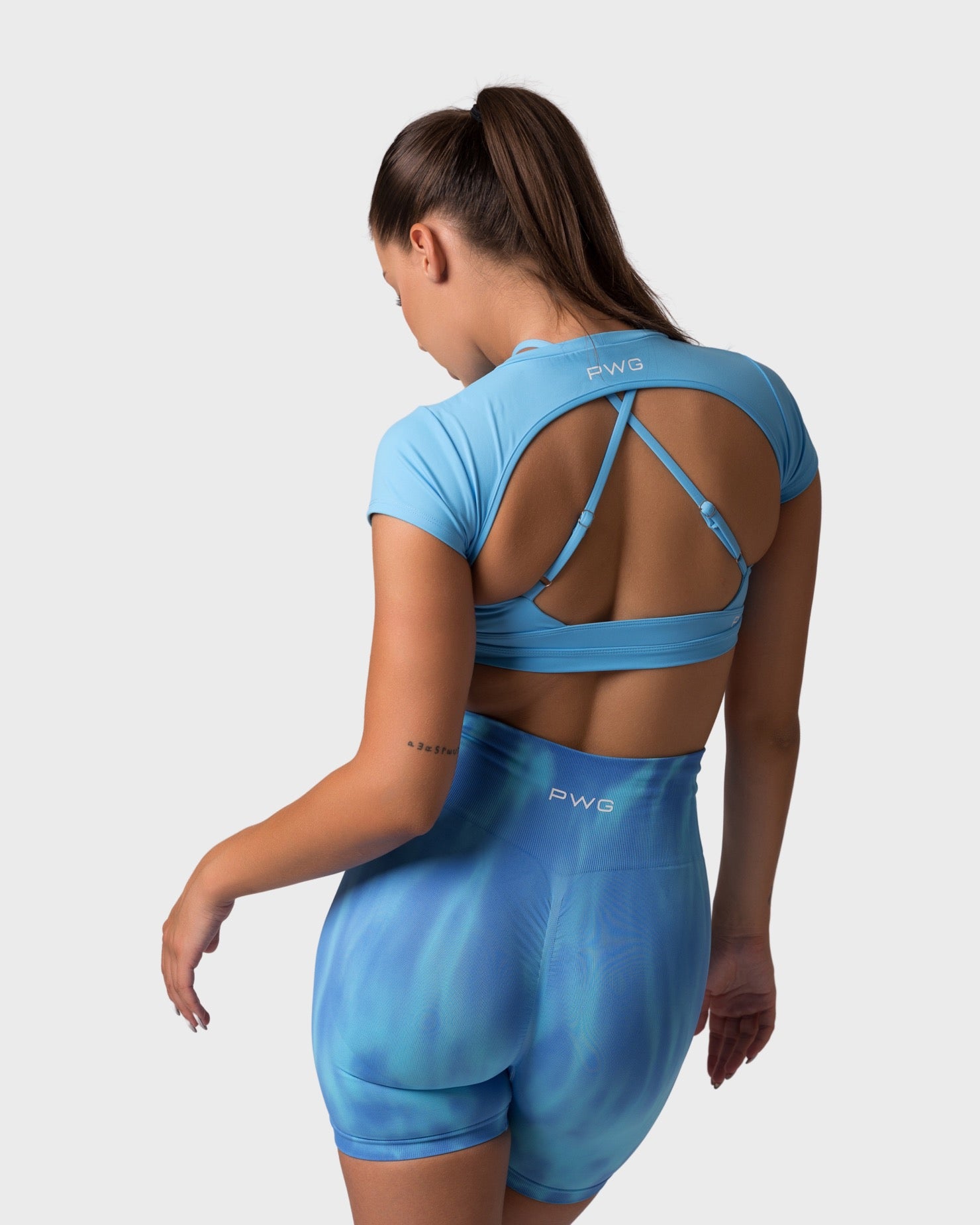 Back view of ocean blue short sleeve top, open-back design with crisscross straps